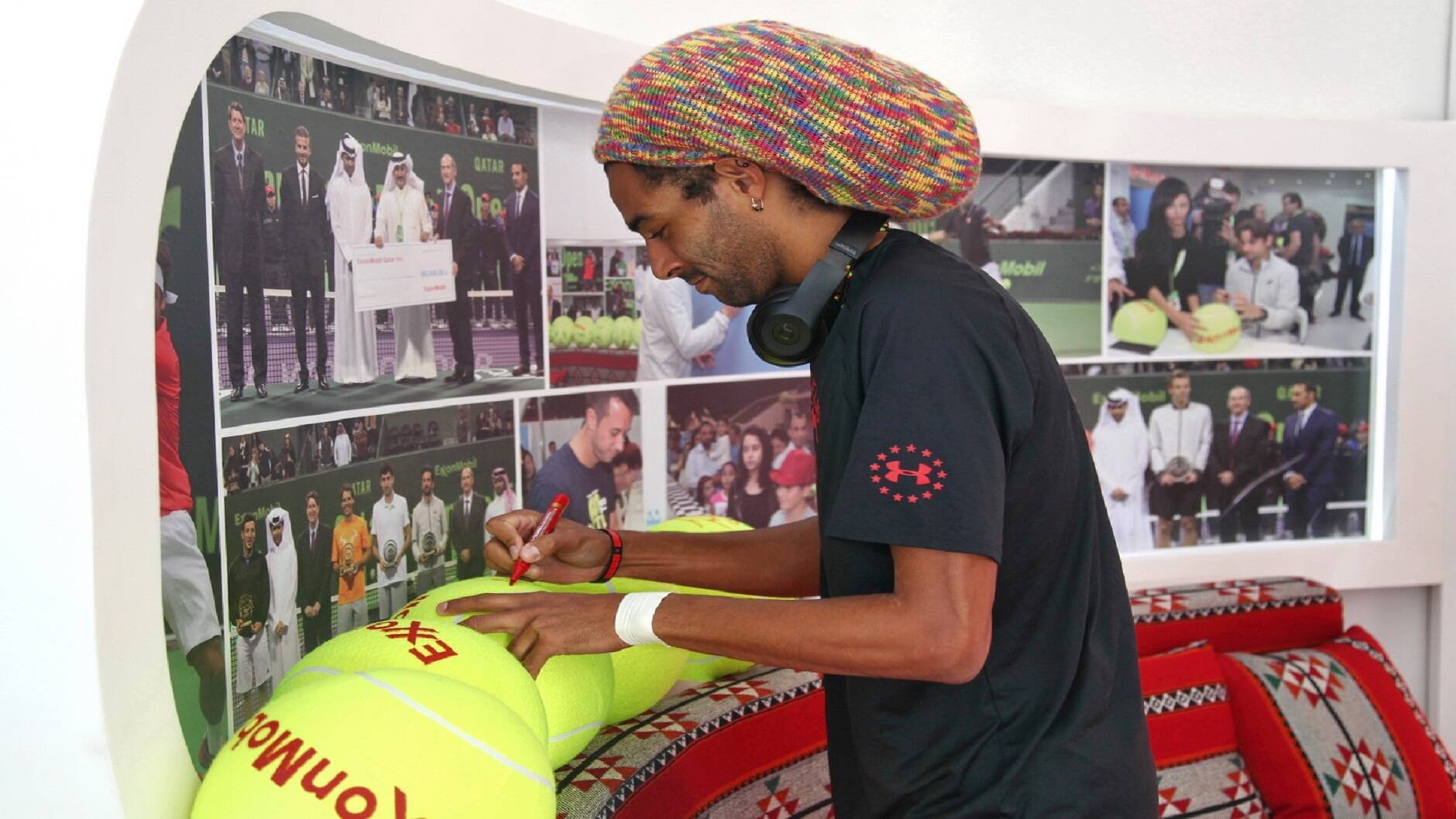 Tennis star Dustin Brown signs souvenir tennis balls for his fans at the ExxonMobil Qatar stand.